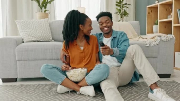 幸福的黑人夫妇，在他们家或房子的客厅里吃爆米花和看电影。爱情，浪漫和男人和女人在看电视和浏览频道时有