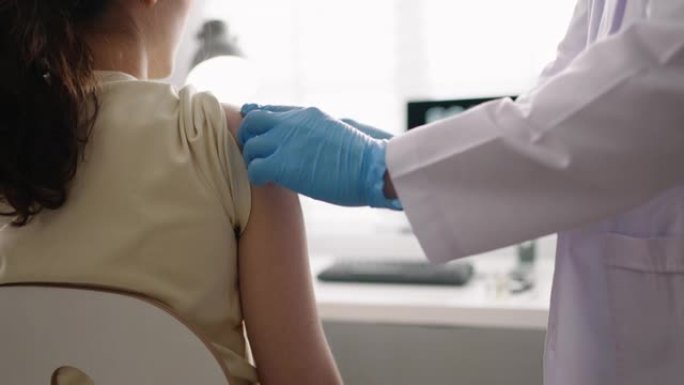 戴着安全手套和防护口罩的护士正在健康诊所向女性患者注射疫苗