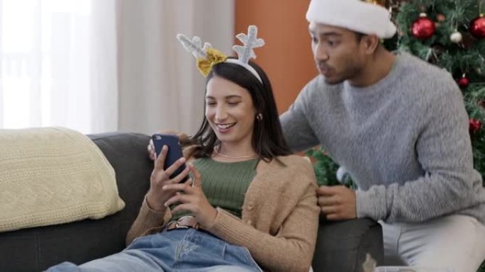 一对年轻夫妇在家中一起在沙发上使用手机进行圣诞节最后一刻购物的4k视频片段