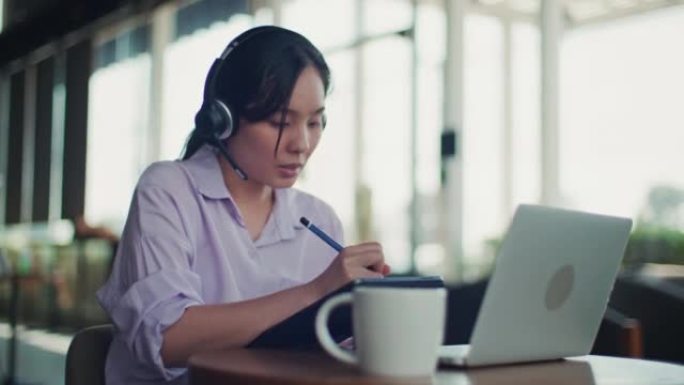 亚洲女性在笔记本电脑上戴无线耳机视频通话