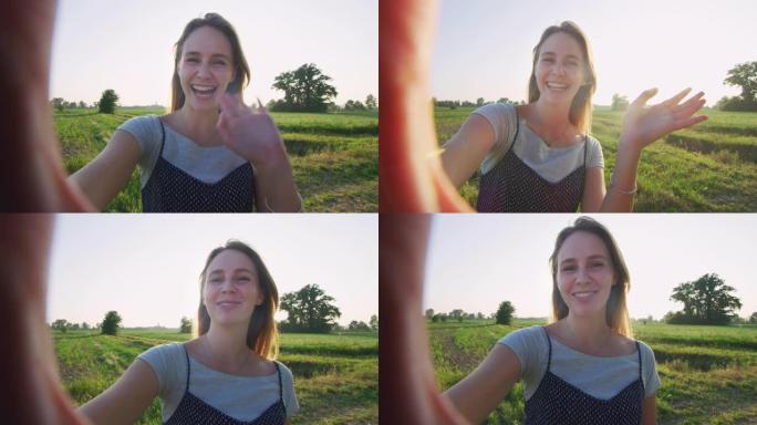 一个年轻的金发幸福的女人的真实镜头正在田野里打视频电话。