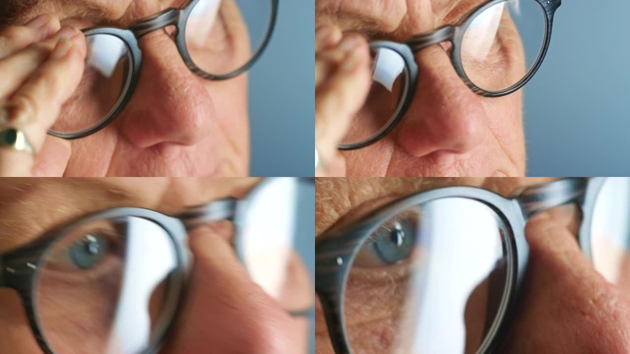 眼镜，视力和高级人士的脸尝试一副新的眼镜，规格或眼镜。在蓝色背景上使用处方镜片的退休人员的变焦宏观，