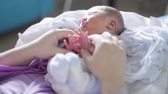 母亲在医院分娩后用手抚摸婴儿的小手