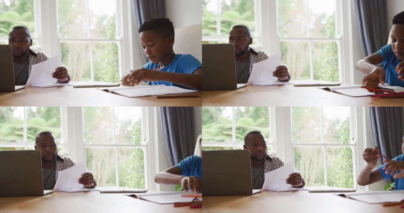 非裔美国人在家里使用笔记本电脑工作，与儿子一起坐在桌子旁做学校工作