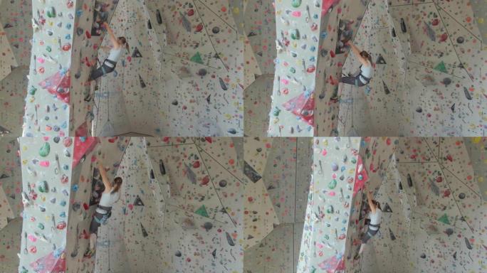 无人机: 年轻的女攀岩者在凉爽的室内训练中心攀爬。