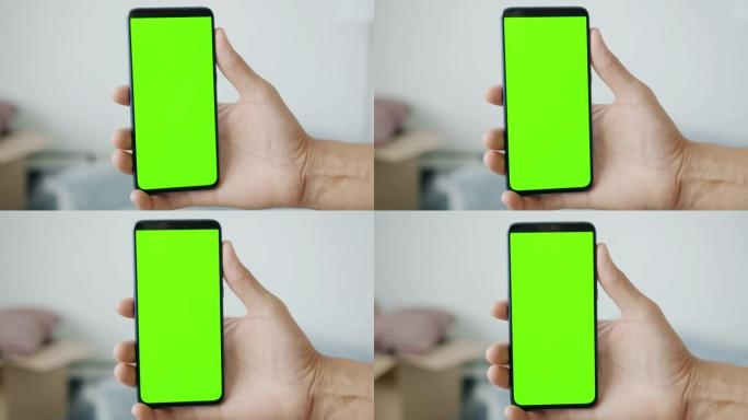 室内男性手持绿色色度键屏幕智能手机的特写