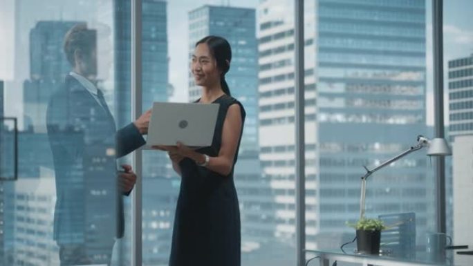 成功的公司首席执行官和投资经理的肖像，站在城市办公室时使用笔记本电脑交谈。两个成功的商人就电子商务营