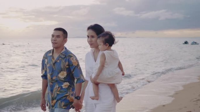 亚洲家庭在日落时带着快乐的情感在沙滩上奔跑。家庭、度假和旅行