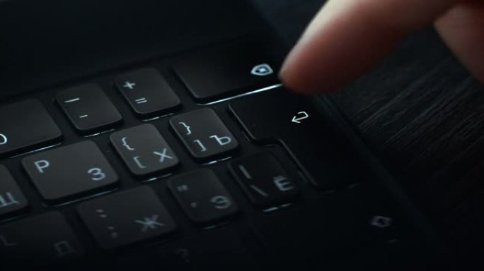 按黑色笔记本电脑键盘上的 “enter” 按钮的人手特写