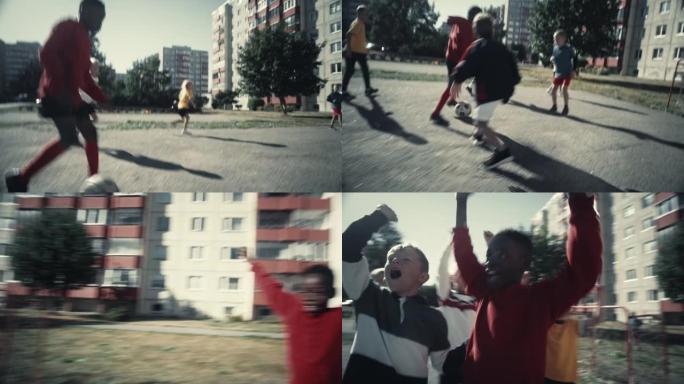年轻的黑人男孩和不同的朋友一起踢足球。多民族的孩子在附近享受足球比赛。球员庆祝进球。快节奏的跟踪镜头