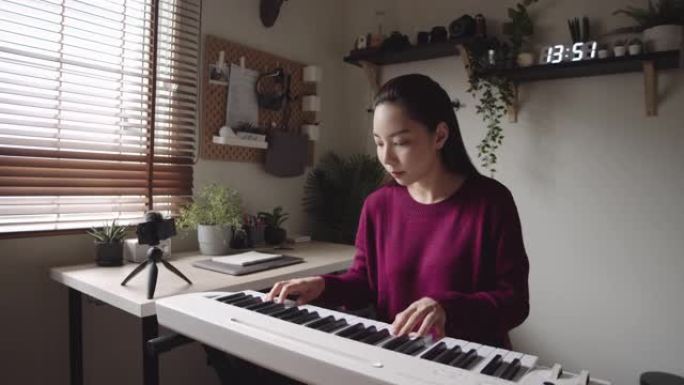 家庭独自键盘钢琴爱好年轻女子用智能手机练习钢琴