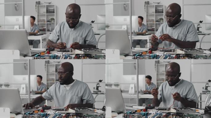 非裔美国工程师用万用表和笔记本电脑测试电子产品