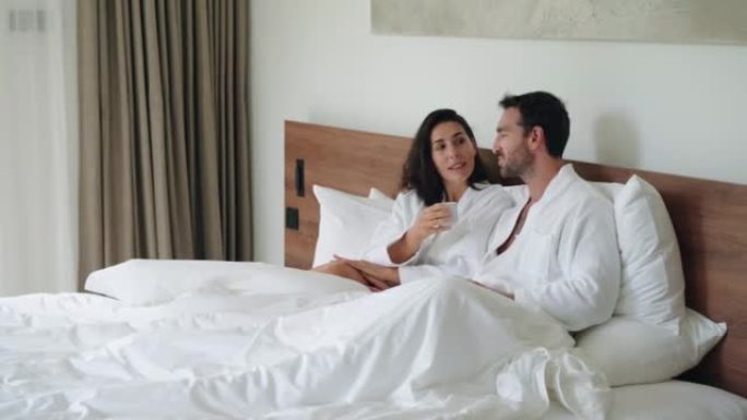微笑的夫妇在床上享受慵懒的早晨