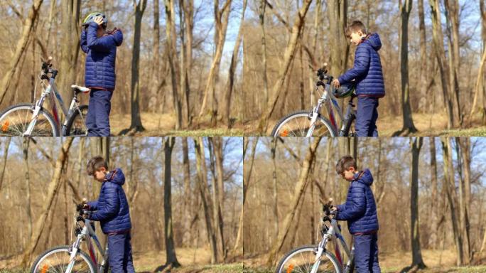 穿着蓝色夹克的男孩站在森林里脱下自行车头盔