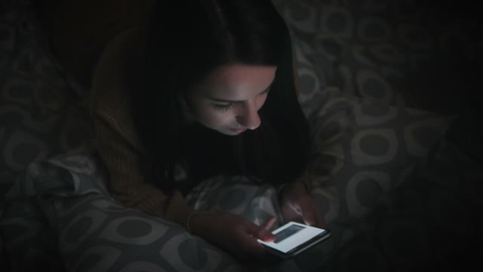 女人深夜在家床上使用手机