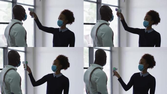 戴着口罩的非裔美国商人在到达办公室时受到同事的体温