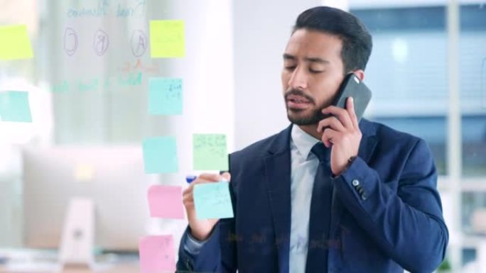 男性办公室职员在电话中写有创意的商业想法。市场经理一边工作，一边打电话，一边在彩色的笔记上写东西。公