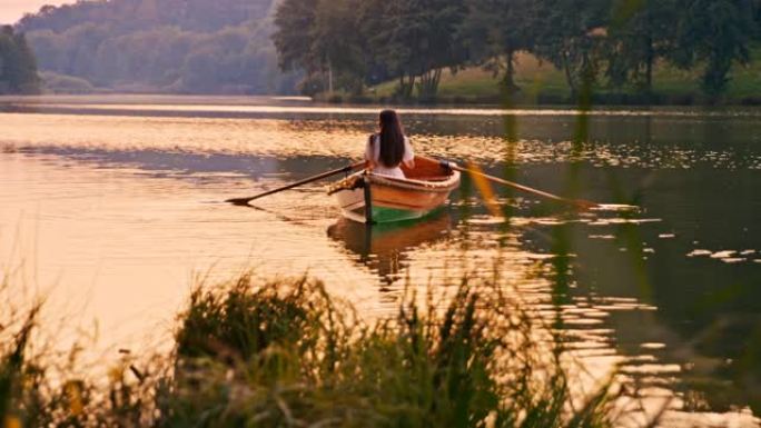 慢动作的年轻女子在装饰的船上划过湖面