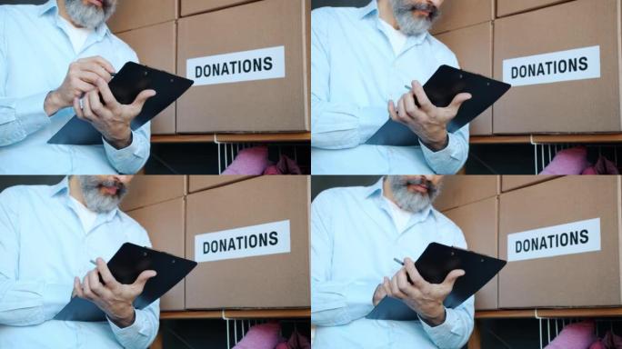 特写慈善基金经理写在剪贴板上做盘点储藏室的捐赠箱