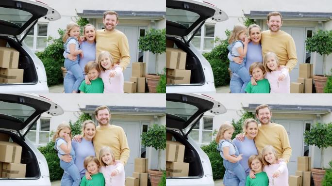 新家外的家庭肖像，在搬家时用钥匙从汽车上卸下箱子