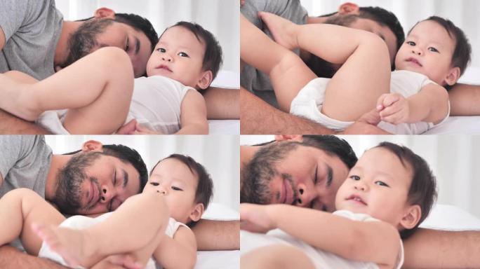 疲惫的千禧一代亚洲父亲睡在床上，想让宝宝儿子睡觉，活跃的宝宝玩一整天。