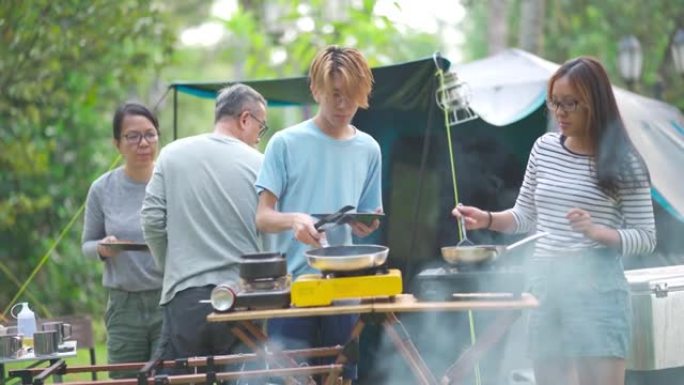 亚洲华裔青少年兄弟姐妹早上在露营时为家人准备早餐