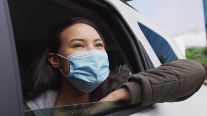 戴着口罩的亚洲妇女坐在车里看着窗外