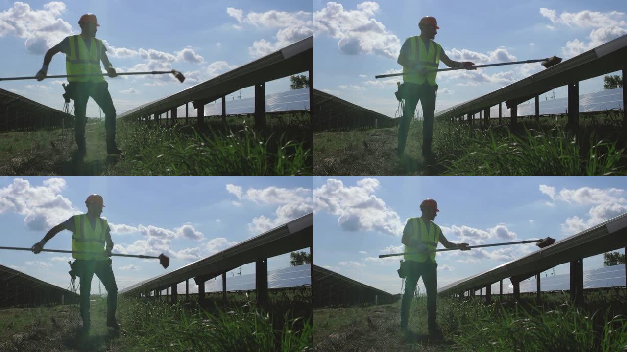 男技术员用扫帚清除太阳能电池板上的灰尘