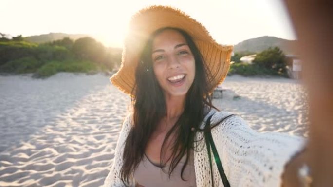 一个快乐的无忧无虑的年轻女性游客戴着草帽，在度假旅行期间，在阳光明媚的日子里，在沙漠近海海边，通过电