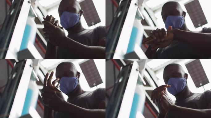 适合戴着口罩的非洲裔美国男子在健身房消毒双手