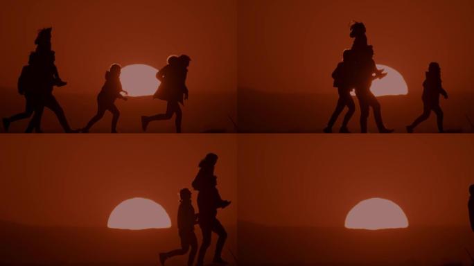 剪影中的SLO MO LS家庭在日落时在山上散步