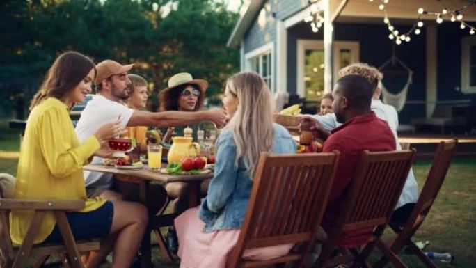 一群多种族的人在户外晚餐时玩得开心，互相交流，吃素食。在温暖的夏日，亲戚和朋友聚集在他们的家外。
