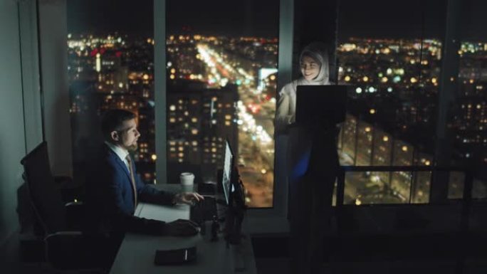 戴着头巾的男人和女人在黑暗的办公室工作到很晚