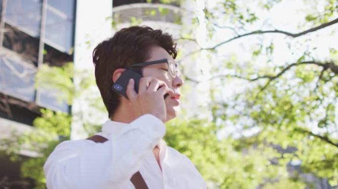 困惑的亚洲男子站在街上用智能手机聊天