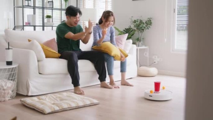 年轻的亚洲夫妇在沙发上与物联网快乐的城市生活乐趣活动。