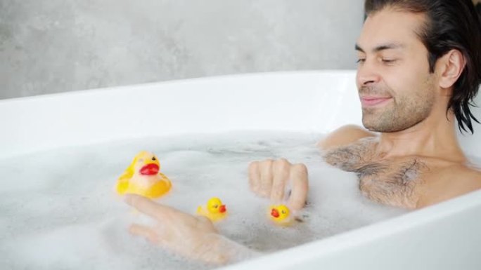 快乐的年轻人独自在浴缸里玩玩具鸭子的慢动作