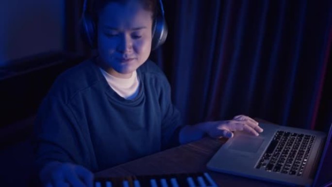 亚洲女音乐家在家庭工作室使用迷你键盘和笔记本电脑