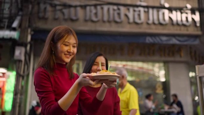 亚洲母女在农历新年在唐人街旅行和吃街头美食。