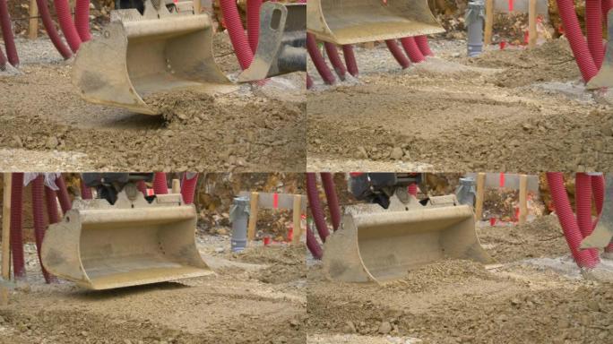 特写: 液压臂在砾石上延伸，并用铲子铲平。