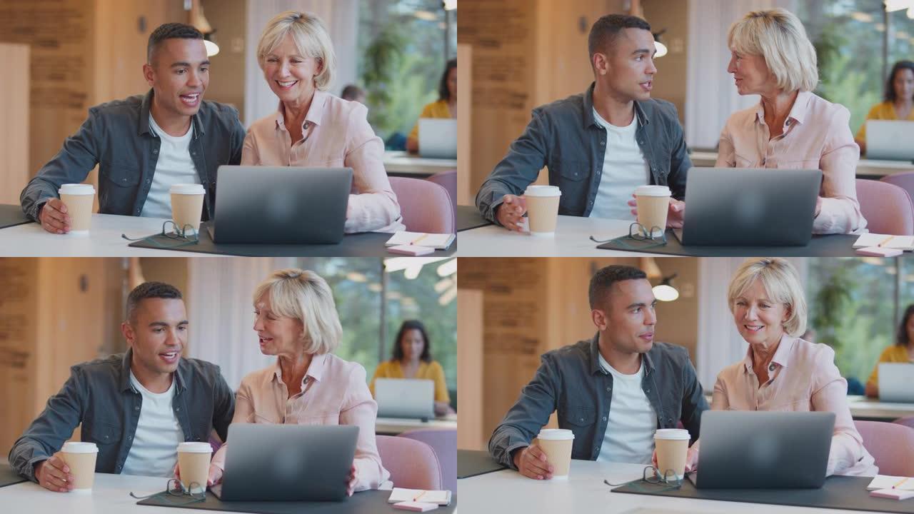 成熟的女商人指导年轻的男性同事在办公桌上使用笔记本电脑