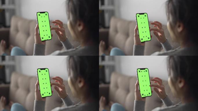 女人使用手机绿屏看手机消息躺在沙发上