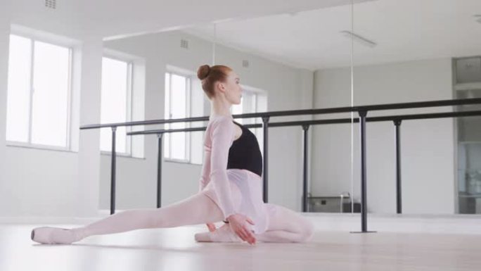 高加索女芭蕾舞演员在地板上伸展并为舞蹈课做准备
