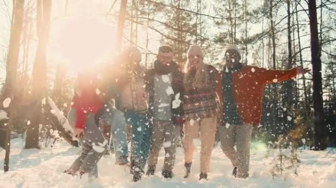 寒假。快乐有趣的多民族朋友摆姿势踢雪，微笑在阳光明媚的森林徒步镜头耀眼慢动作。