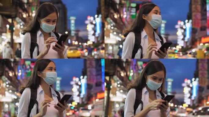 年轻的亚洲妇女戴口罩和使用手机寻找地图