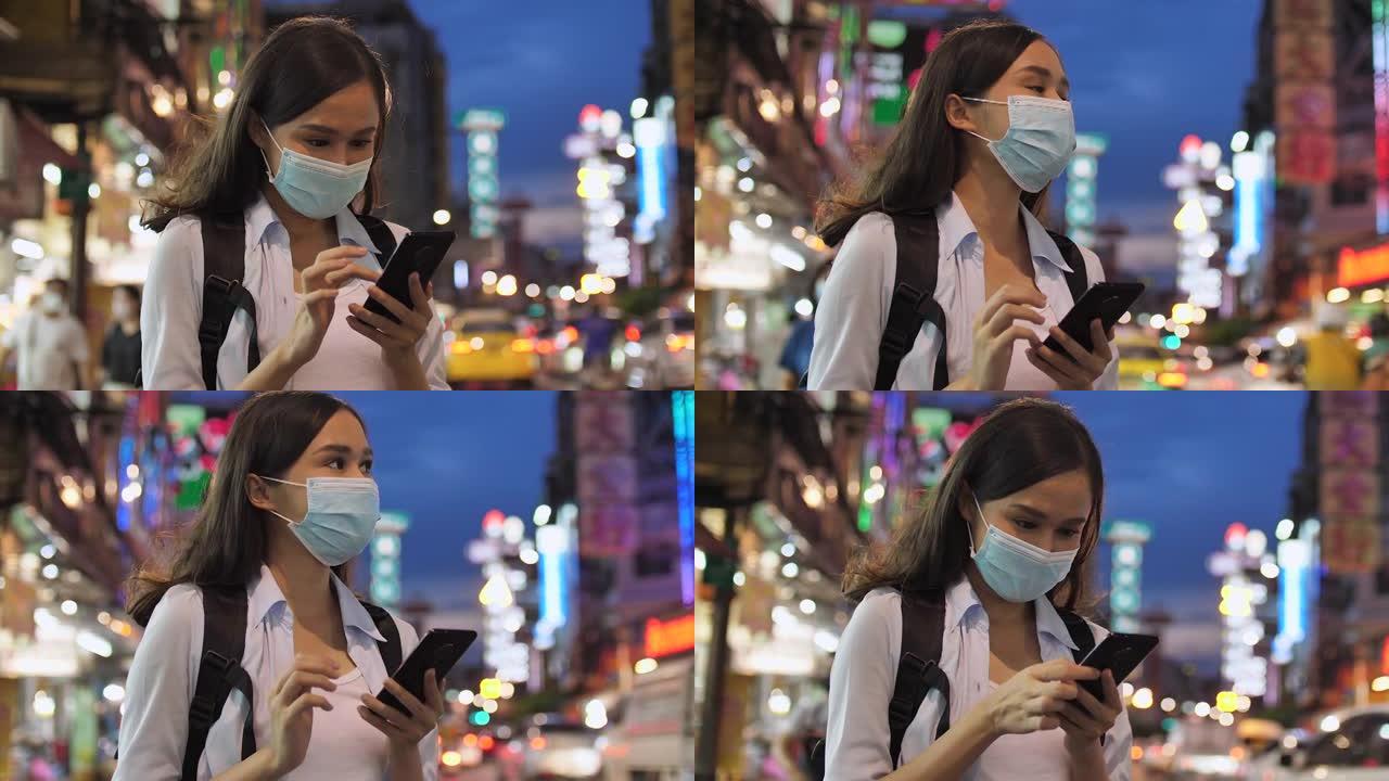年轻的亚洲妇女戴口罩和使用手机寻找地图