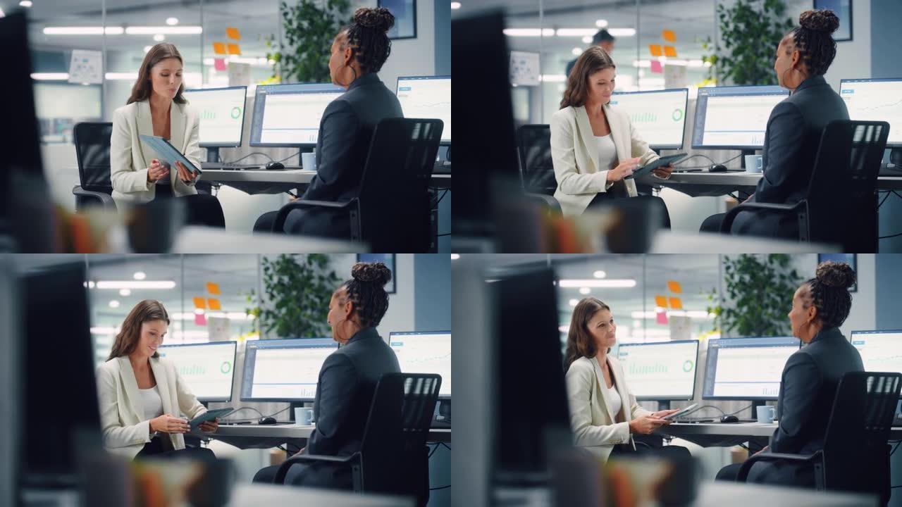 两名女同事亲切地交谈，微笑着在各种现代商务办公室的笔记本电脑上展示工作。经验丰富的经理和年轻员工讨论