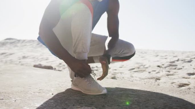 非裔美国人在海滩上户外运动时系鞋带的中段
