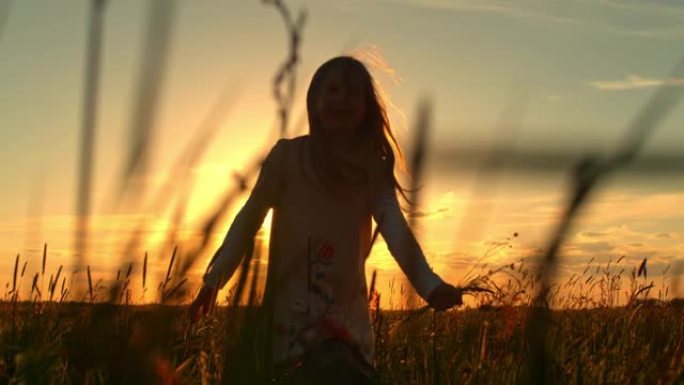 日落时在草地上奔跑的超级SLO MO小女孩