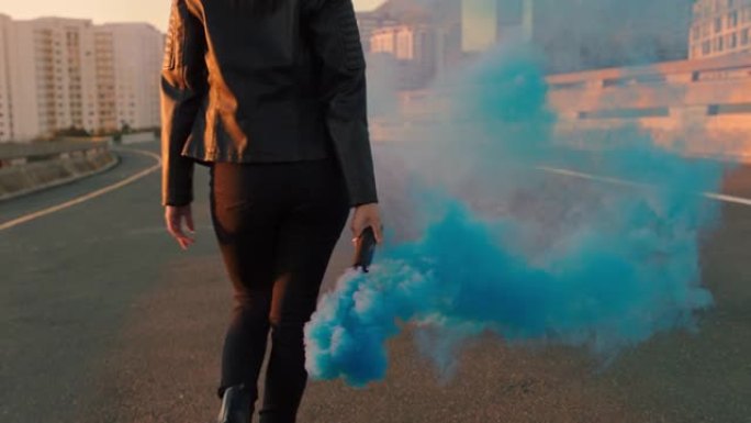 自信的女人手持烟雾弹在日出时在城市街道上行走叛逆的女性活动家抗议