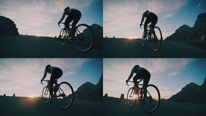 骑自行车的人在日出时在山路上坡骑自行车